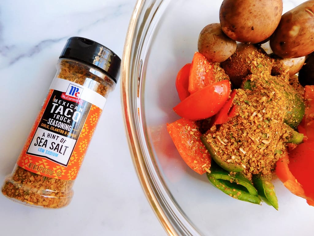 An assortment of veggies in a bowl with a container of McCormick Mexican Taco Truck Seasoning