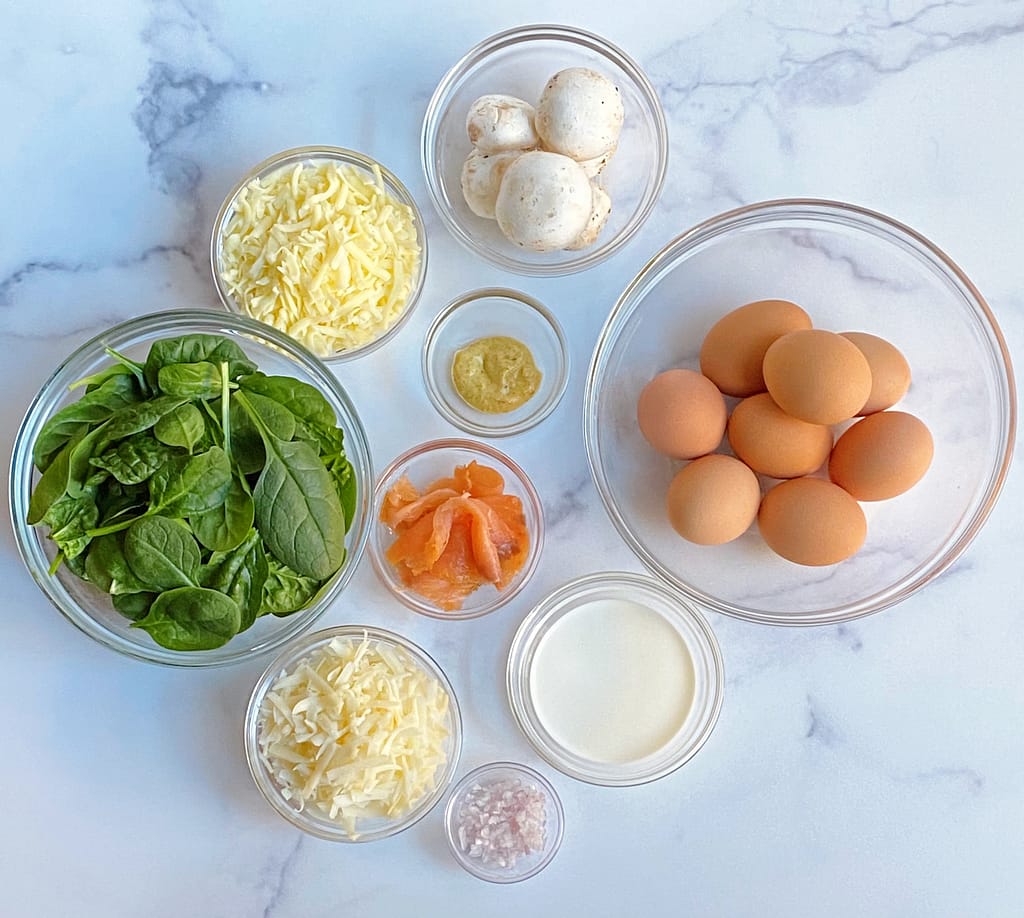 All of the ingredients used in the Spinach, Mushroom and Smoked Salmon Cheese Frittata in separate bowls
